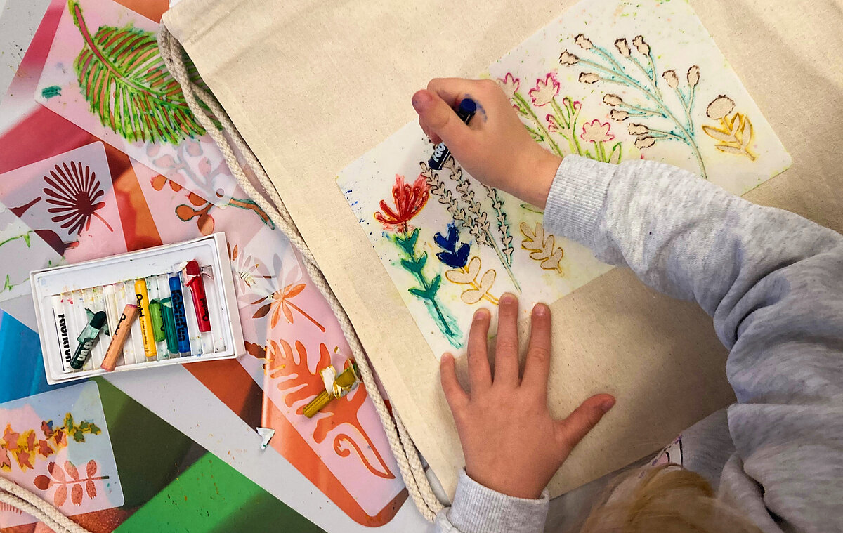 Kind malt eine bunte Stofftasche an