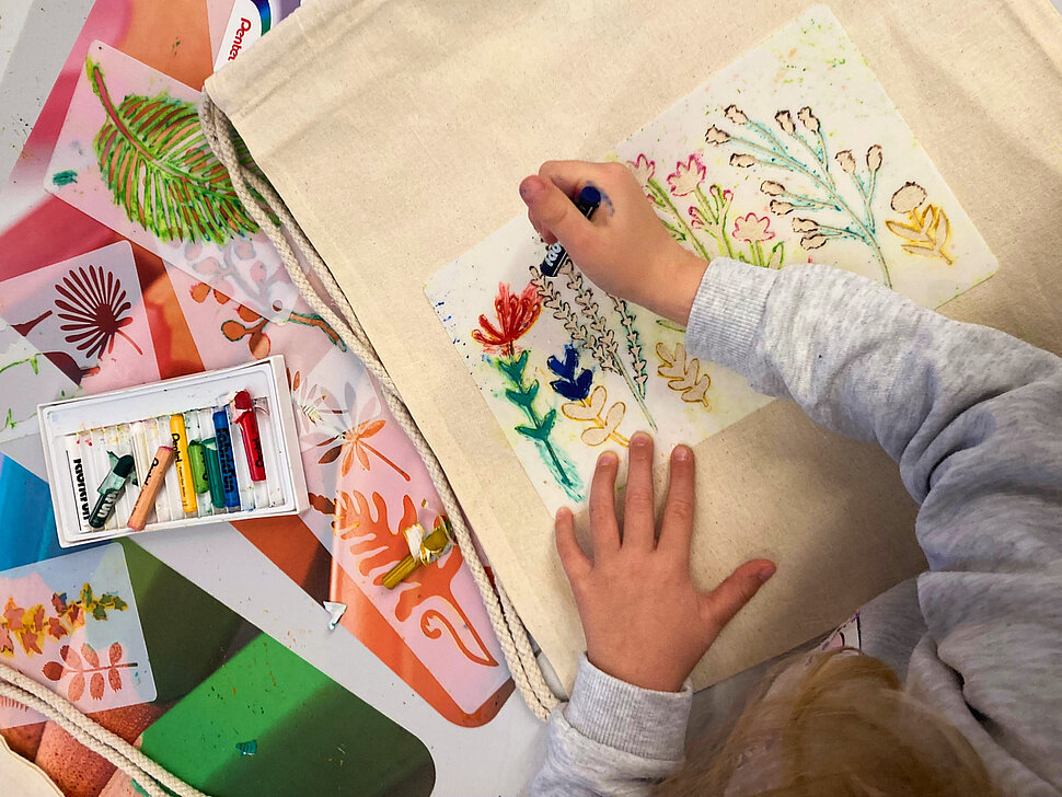 Kind malt eine bunte Stofftasche an
