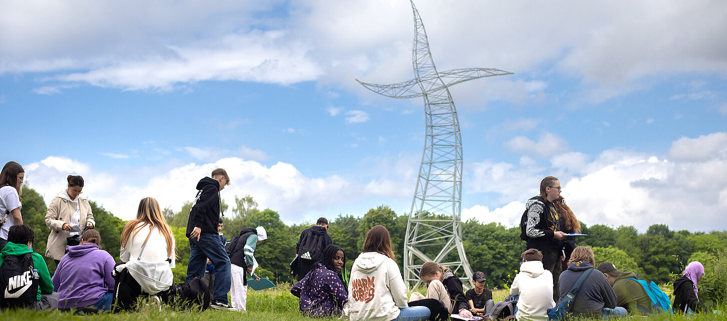 Eine Schulgruppe vor dem Zauberlehrling auf einer Wiese