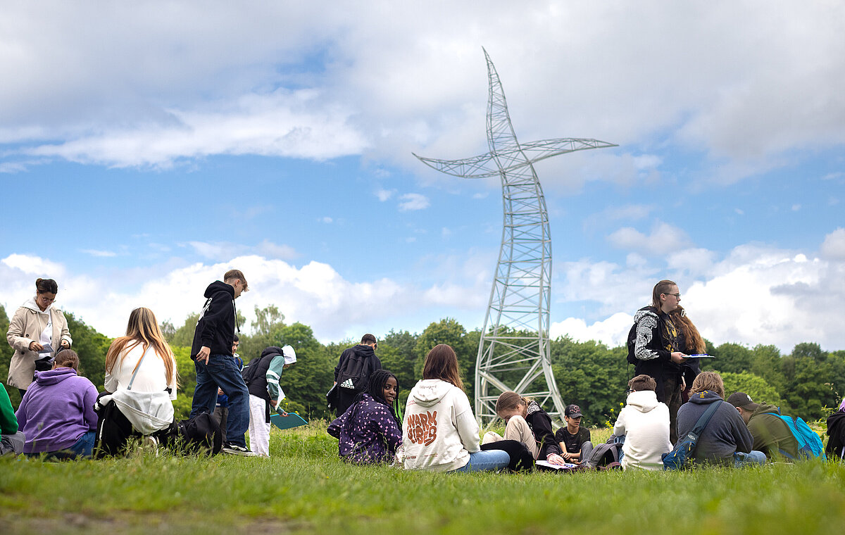 Eine Schulgruppe vor dem Zauberlehrling auf einer Wiese