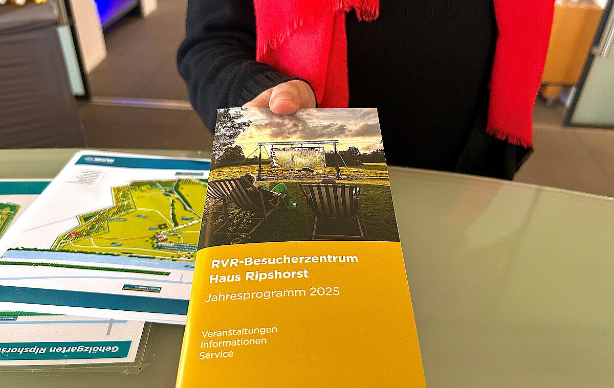 Ein Gast bekommt das Jahresprogramm 2025 vom Haus Ripshorst überreicht