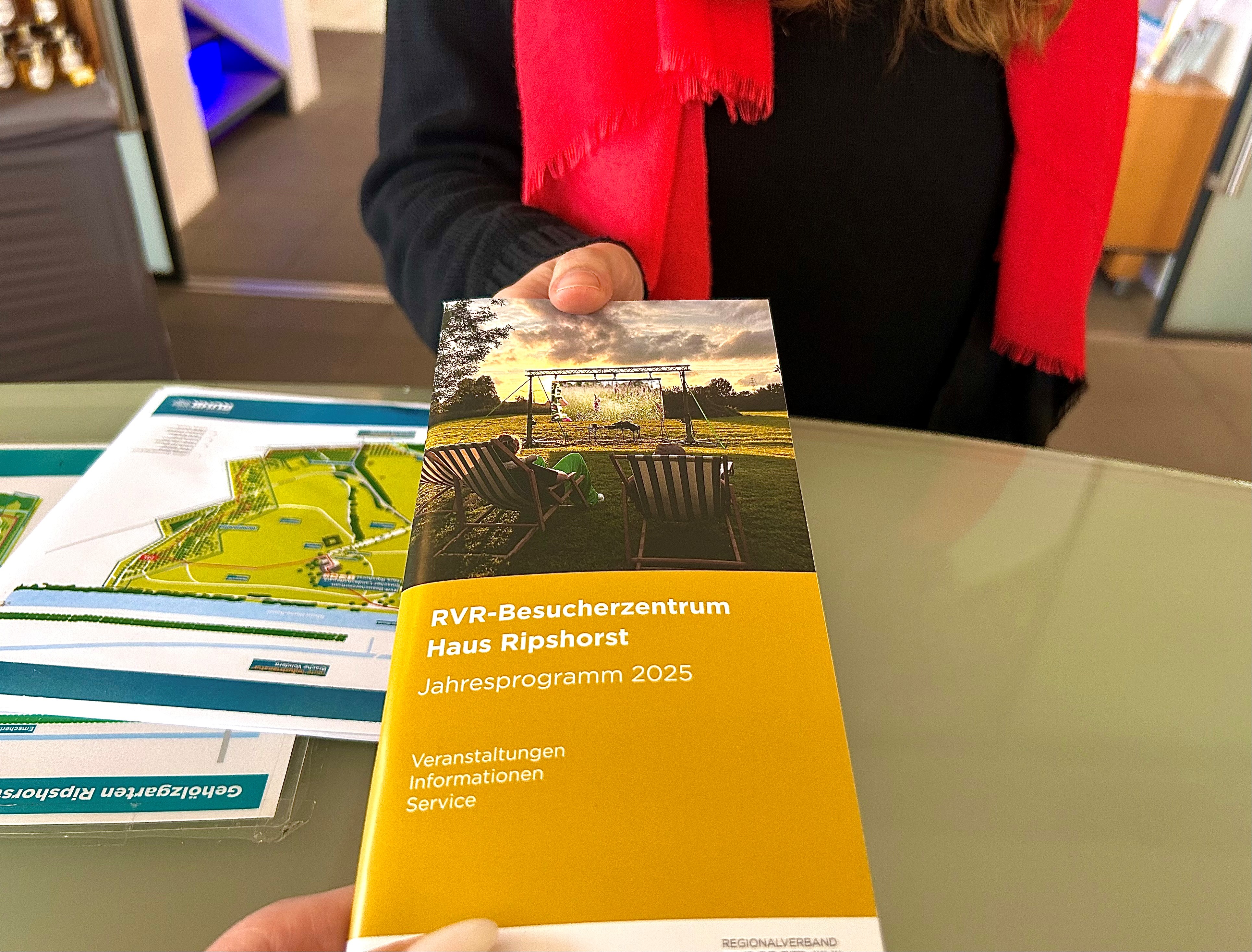 Das Jahresprogramm 2025 wird einem Gast gereicht
