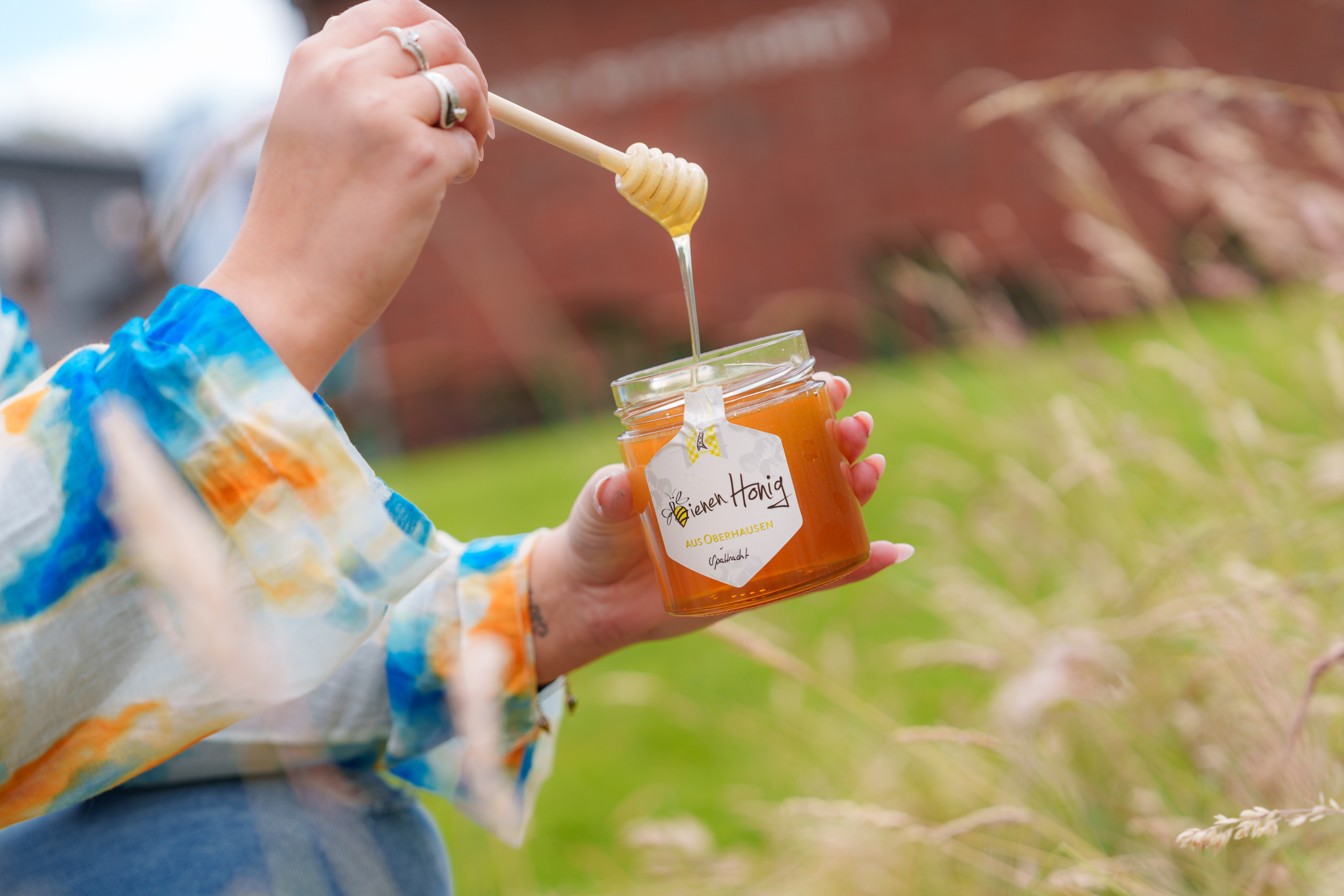 Ein volles Glas Honig wird umgerührt.