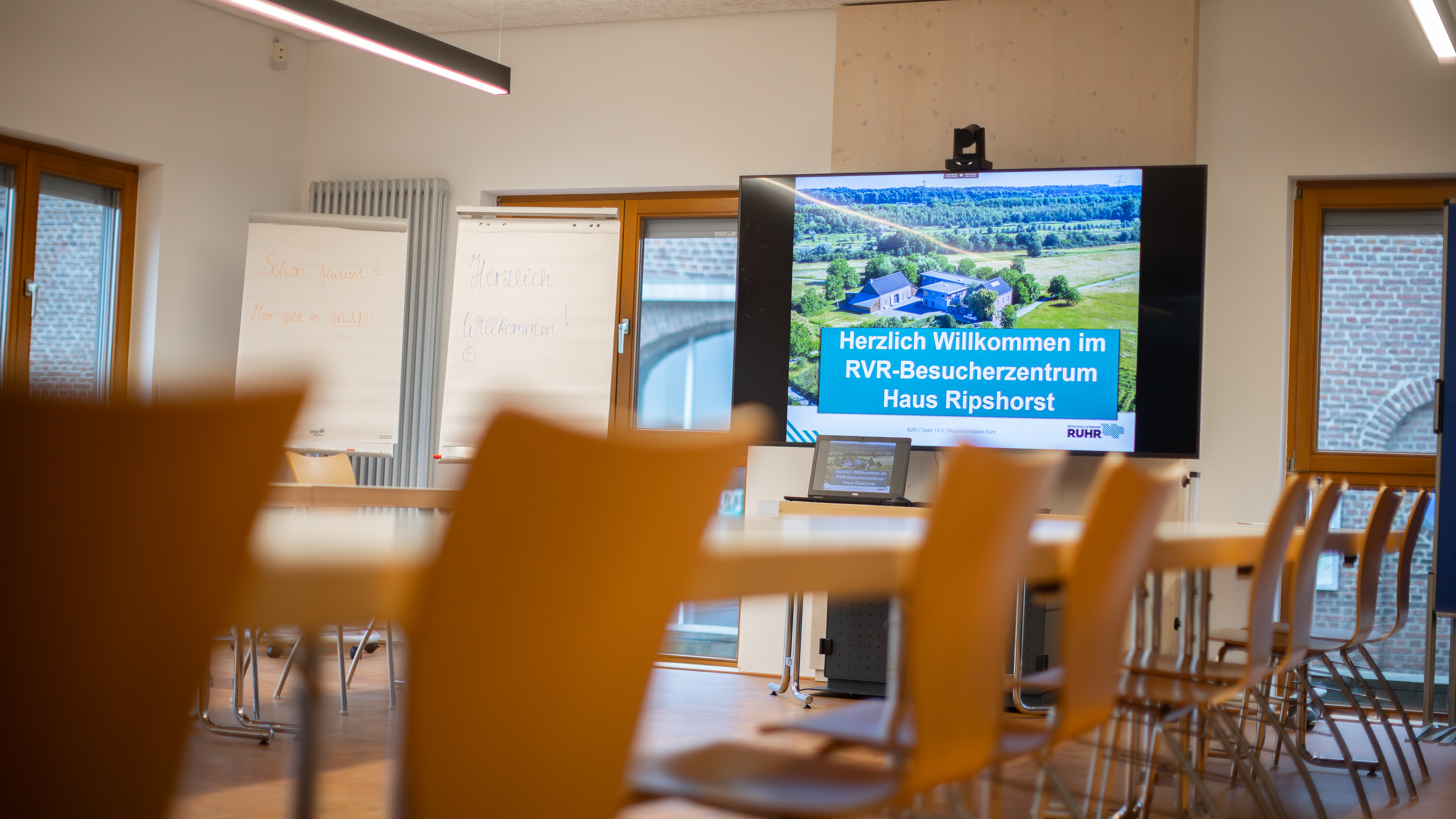 Der Seminarraum mit großem Monitor auf dem eine Präsentation zu sehen ist
