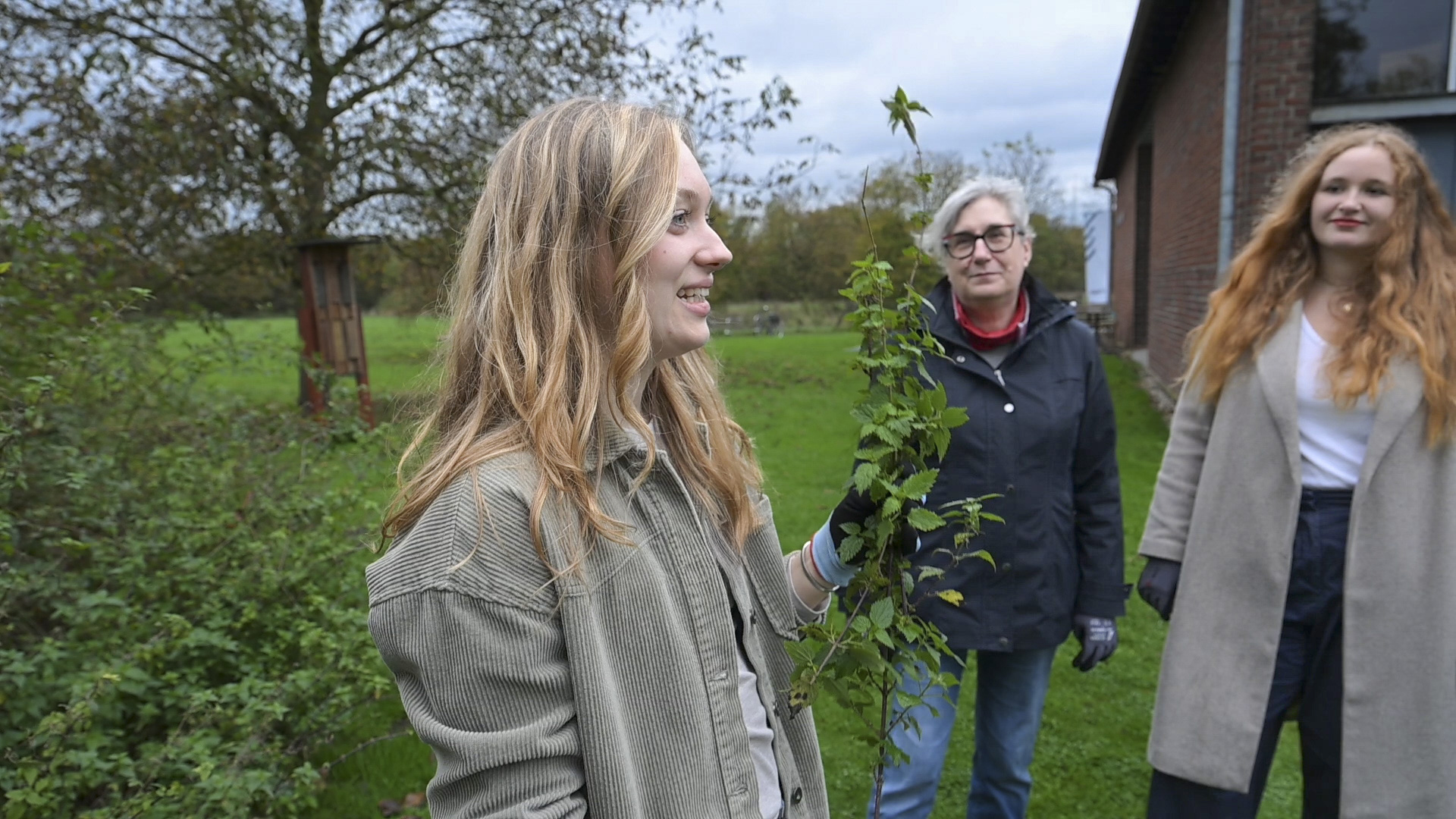 Eine Kursleitung erklärt etwas über die Brennnessel während sie diese in der Hand hält