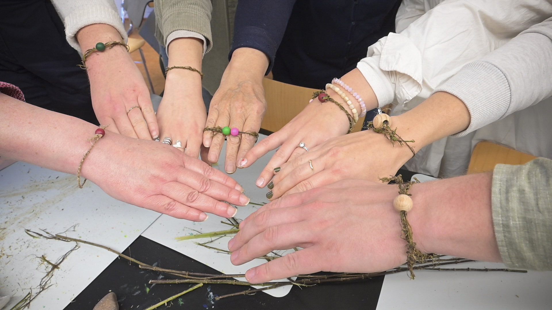 Mehrere Hände zeigen zusammen die selbstgemachten Brennnesselarmbänder