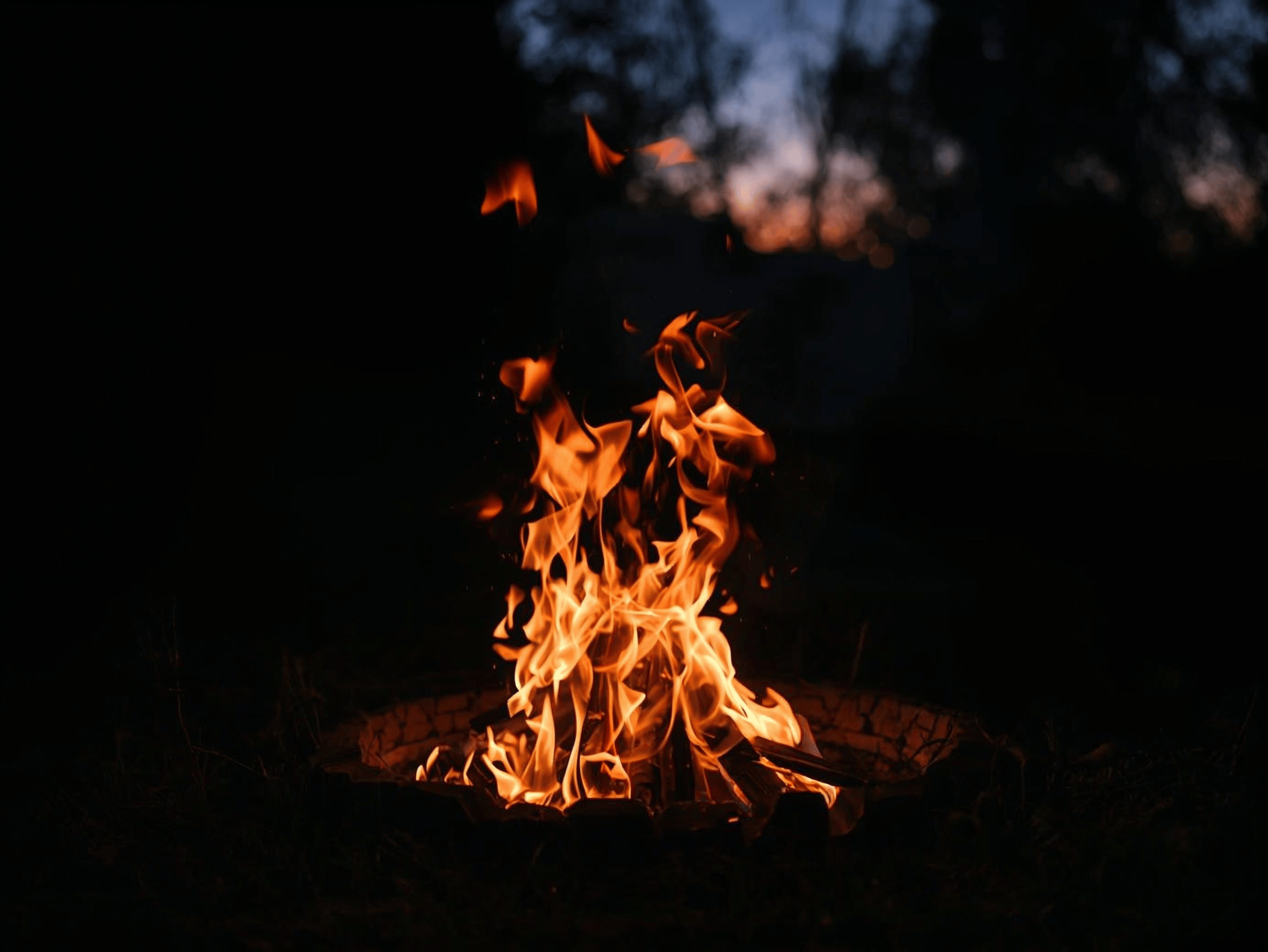Ein Lagerfeuer brennt nachts in einer Feuerschale